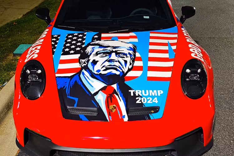 Nắp capo cũng được dán hình ảnh ông Trump, đi kèm các khẩu hiệu quen thuộc như "Trump 2024", "God Bless America" cũng như hình ảnh lá cờ Mỹ với logo USA.