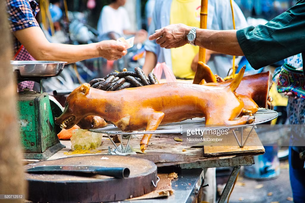 Một người đàn ông mua thịt chó tại quầy hàng ở vỉa hè. Ảnh: Getty.