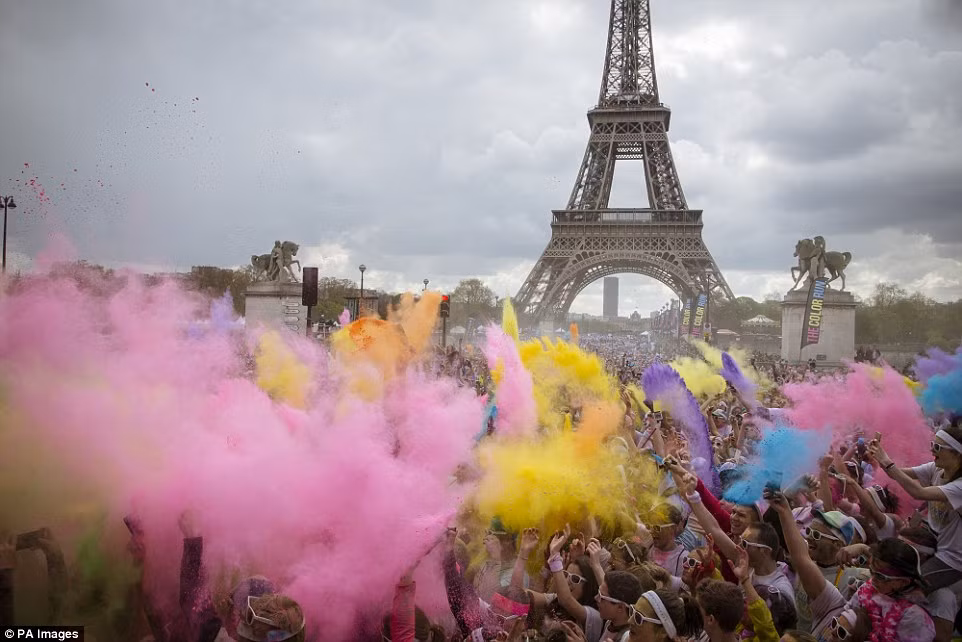 Mọi người tung bột màu vào nhau khi về đích dưới chân tháp Eiffel. (Nguồn: Daily Mail)