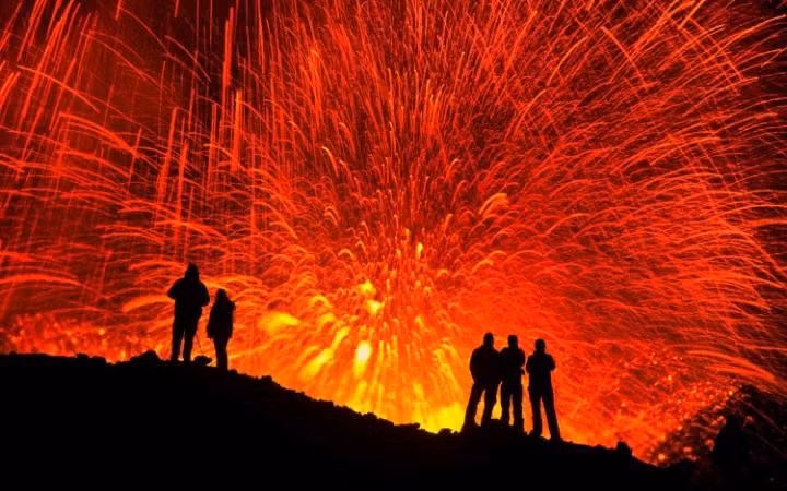 Một nhóm du khách chiêm ngưỡng cảnh tượng núi lửa Fimmvörðuháls phun trào dung nham trong đêm. (Nguồn: Telegraph)