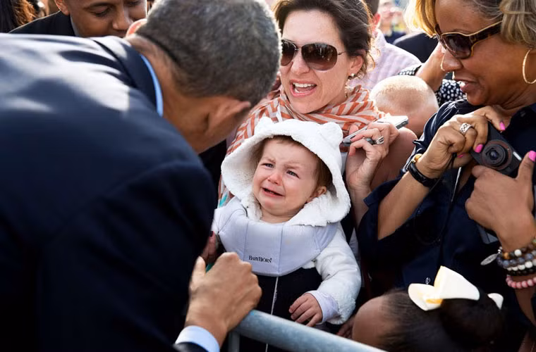 Bé trai òa khóc trong lúc cha mẹ đưa em tới để chào đón ông Obama.