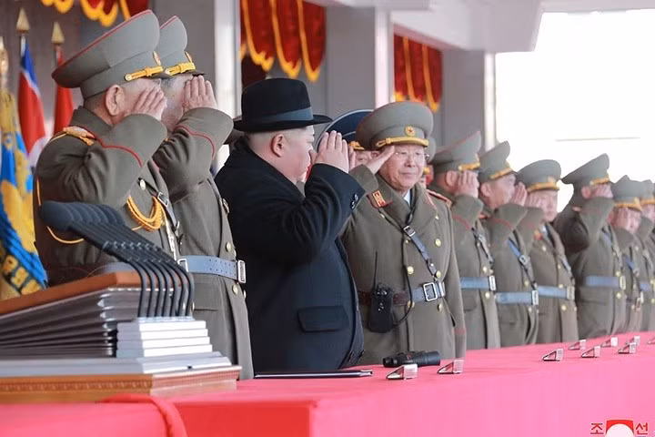 Ông Kim Jong-un và các tướng lĩnh cùng giơ tay chào lực lượng quân đội tham gia diễu hành. Ông Kim đội thêm mũ, do thời tiết khi đó ở Bình Nhưỡng rất lạnh (âm nhiều độ C).