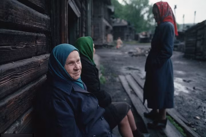 Phụ nữ Siberia ngồi trước nhà trong không khí ảm đạm.