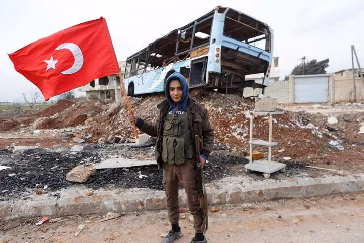 Một chiến binh thuộc “Quân đội Tự do Syria” (phe đối lập Syria) làm “nội ứng”, phất cờ Thổ Nhĩ Kỳ khi anh ta đi tuần ở Azaz, Syria.
