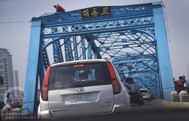 Dàn ô tô di chuyển qua cây cầu sông Datong mới được sơn lại. Việc sơn lại cây cầu này là hoạt động nhằm hưởng ứng dịp kỉ niệm 70 năm ngày thành lập Đảng Lao động Triều Tiên.