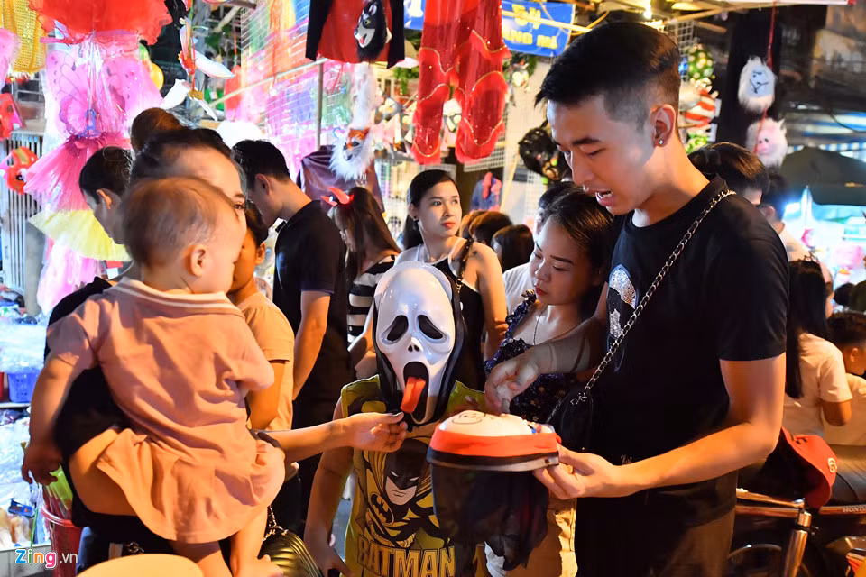 Một gia đình đang chọn mua cho trẻ nhỏ chiếc mặt nạ hình đầu lâu theo ý thích của con.