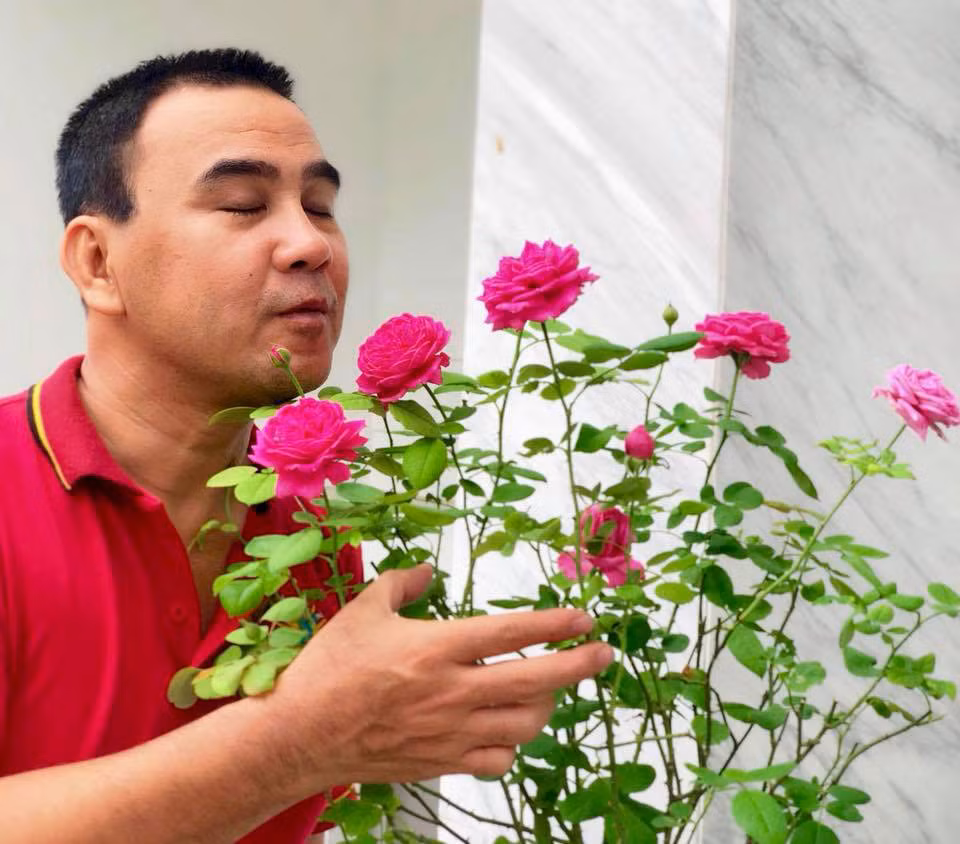 Quyền Linh vui vẻ tạo dáng bên khóm hoa hồng.