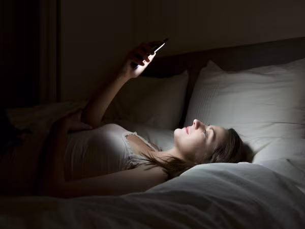 9. Bạn đang sử dụng điện thoại trên giường: Ánh sáng từ điện thoại có thể ngăn cản cơ thể bạn tạo ra melatonin, hormone ngủ. Giữ điện thoại thông minh, thiết bị điện tử gần mặt có thể gây rối loạn giấc ngủ. Đây là một trong những lý do để thức dậy vào ban đêm. Ảnh: Boldsky.