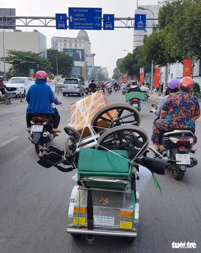 Nhìn từ phía sau, khó có thể thấy được người đàn ông nhỏ bé đang gồng mình chở cả một chiếc xe hàng nặng trĩu ân tình - Ảnh: NGỌC HIỂN