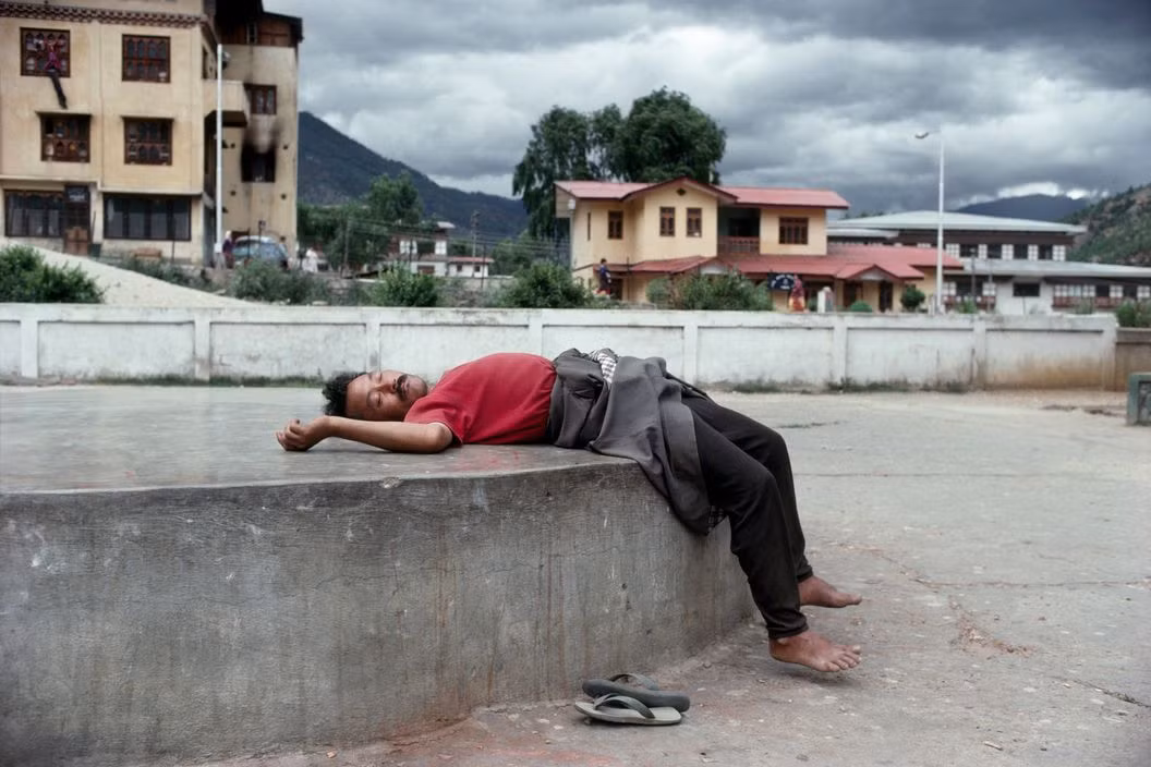 Tư thế ngủ lạ lùng trên đường phố của một người đàn ông ở thủ đô Thimphu. Ảnh: Martin Parr/ Magnum Photos.