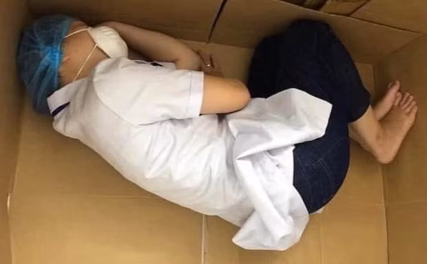 Nữ nhân viên y tế Đà Nẵng nằm ngủ tạm bợ trên tấm bìa các tông sau ngày dài chăm sóc bệnh nhân. Dù đang cố chợp mắt lấy lại sức nhưng nữ điều dưỡng này vẫn không quên đeo đồ bảo hộ như trùm mũ, khẩu trang, hình ảnh này đã lấy đi nước mắt của nhiều người.