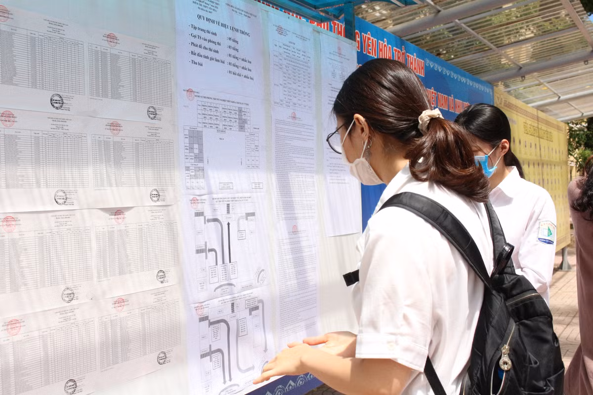 Một em học sinh tra số báo danh, số phòng thi và sơ đồ nhà trường để xác định vị trí phòng thi.