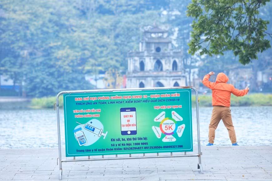 Người dân tập thể dục ngày đầu năm trên hồ Hoàn Kiếm vẫn phải thực hiện các biện pháp phòng chống dịch. (Ảnh: Tuấn Anh/TTXVN)