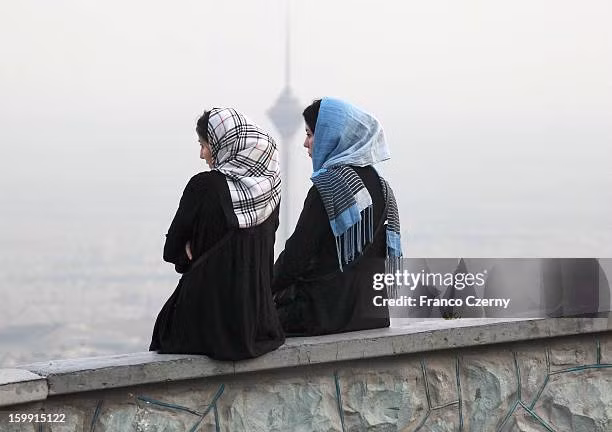 Hai cô gái trẻ người Iran ngồi trò chuyện, phía sau họ là tháp Milad, ngày 28/08/2012.