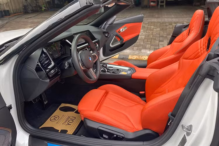Mở mui mềm của xe BMW Z4 từng thuộc sở hữu Minh "Nhựa" sẽ thấy nội thất xe được bọc da đỏ cam cùng với đó là hàng loạt chi tiết nhựa và nhôm. Xe có trang bị màn hình đa thông tin dạng kỹ thuật số có kích thước 10,25 inch, hệ thống âm thanh 12 loa Harman Kardon.