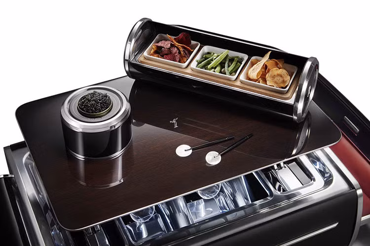 Bởi những đại gia siêu giàu có thể không muốn liên tục giữ trên tay một trong 4 chiếc ly thủy tinh đẹp mắt, chiếc vali có hẳn một cái bàn gỗ nhỏ Tudor Oak – hoàn thiện với khung thép chống gỉ cắt laser – mà dựng lên với chỉ một nút bấm.
