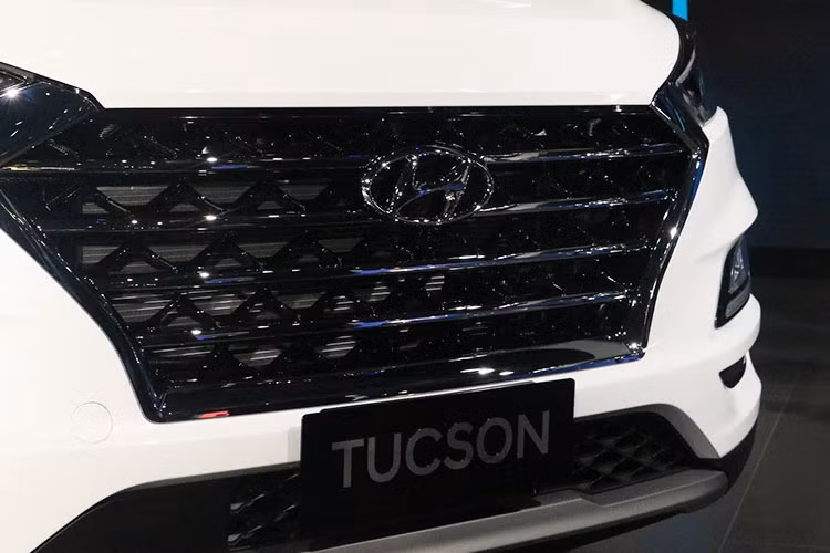 Tucson 2019 là bản nâng cấp giữa vòng đời, xe được thiết kế theo phong cách “Cascading” đặc trưng của Hyundai. Tấm lưới tản nhiệt ở phiên bản lần này cứng cáp hơn với 4 thanh ngang mạ chrome xếp song song, cùng cặp đèn pha LED được mở rộng từ hai góc trên. Bên dưới, bộ đèn sương mù được thu nhỏ, bao quanh bởi dải đèn LED hình chữ L.