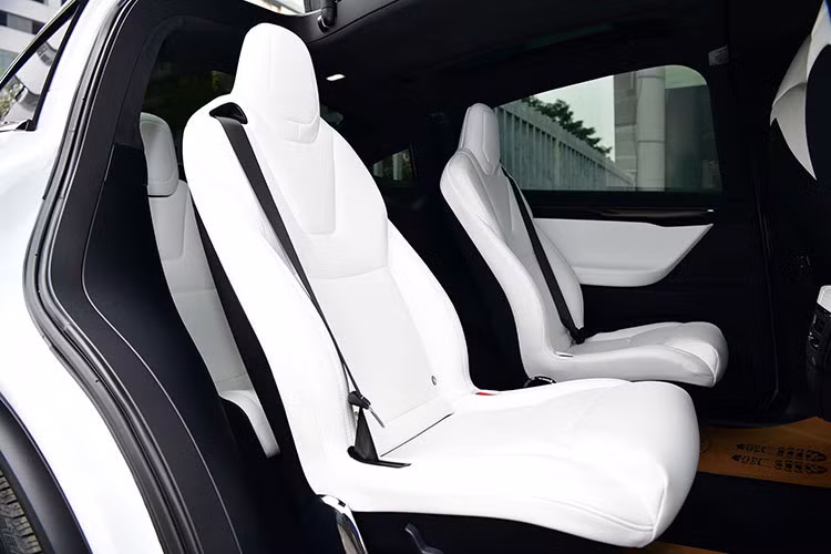Vô-lăng của xe được bọc da, thiết kế 3 chấu tích hợp một số phím chức năng. Chiếc Tesal Model X P100D này có thiết kế 6 chỗ ngồi, tất cả đều được bọc da cao cấp màu trắng trùng màu ngoại thất. hai hàng ghế đầu có khả năng chỉnh điện. 2 ghế ở hàng thứ 2 thiết kế tách rời nhau tạo lối đi khá rộng xuống hàng thứ 3. Hàng ghế cuối dành cho 2 người ngồi với 2 khay để cốc đặt giữa.