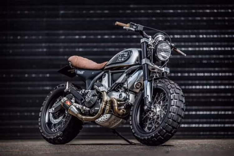 Chiếc môtô Ducati Scrambler siêu ngầu trong bản độ bánh to cực chất đến từ xưởng Down &amp; Out Café Racers (D&amp;O), một xưởng chuyên độ "bánh bedos" cho các mẫu xe phân khối lớn tại Anh quốc, nơi chủ yếu áp dụng cho những chiếc Triumph Bonneville.