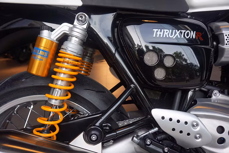 Các tấm ốp hai bên thân xe có hình dáng giống Bonneville T120, nhưng sở hữu những đường gân và các lỗ tròn bọc lưới thép cá tính hơn. Điểm đáng giá của Thruxton R so với phiên bản thường đó là phuộc sau của chiếc xe do hãng Ohlins nổi tiếng cung cấp, đem tới cho chiếc xe khả năng điều khiển một cách chính xác.