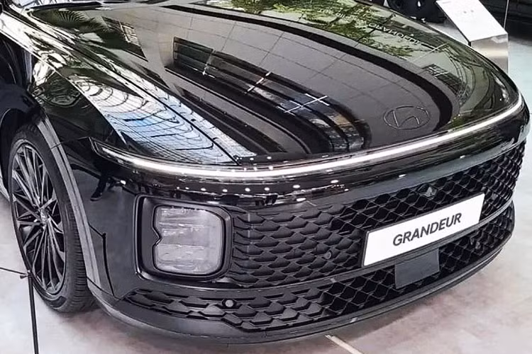 Trên đầu xe, mẫu sedan hạng trung này được trang bị lưới tản nhiệt và hốc gió trung tâm đều được thiết kế hình chữ nhật cỡ lớn với mắt lưới dạng mắt cáo. Nằm giữa 2 chi tiết này là nẹp khá mỏng, sơn cùng màu thân xe. Tiếp đến là cụm đèn pha nằm dọc mới và dải đèn LED định vị ban ngày vắt ngang đầu xe, tương tự cặp đôi xe đa dụng Hyundai Stargazer và Staria.