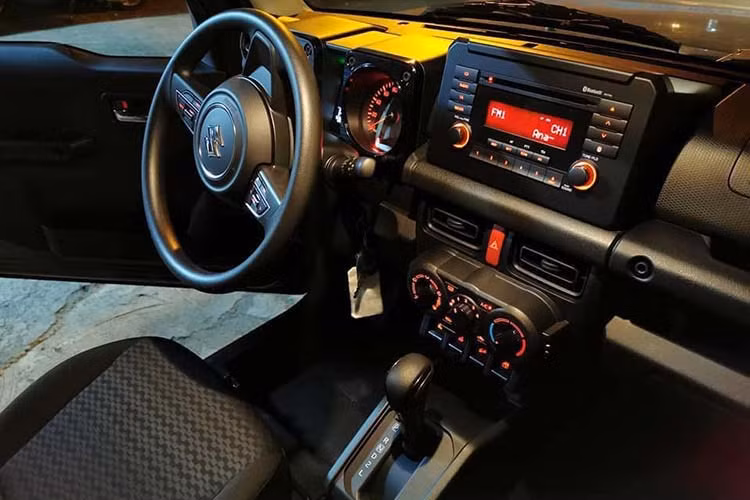 Bên trong Suzuki Jimny 2019 mới, khách hàng sẽ tìm thấy những trang bị như vô lăng 3 chấu bọc da, chỉnh điện 2 hướng, tích hợp phím chức năng, cửa sổ chỉnh điện bên ghế lái, khóa điều khiển từ xa, hệ thống điều hòa tự động với lọc không khí, màn hình đa thông tin trong bảng đồng hồ, tay nắm cửa mạ crôm, ghế bọc nỉ màu đen, ghế lái chỉnh tay 6 hướng...
