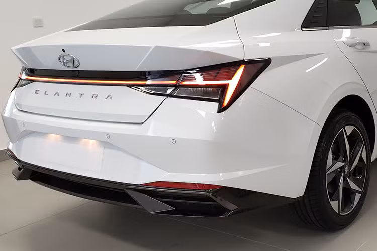 Dáng vẻ coupe hiện rõ khi quan sát từ đuôi xe Hyundai Elantra 2021 với phần kính chắn gió kéo dài xuống nắp ca-pô. Trung tâm là dải đèn LED nối liền cụm đèn hậu với đồ hòa bắt mắt là chi tiết cải tiến so với "người tiền nhiệm". Cản sau của Hyundai Elantra mới có thiết kế khí động học, ống xả giả 2 bên giúp chiếc sedan này cân đối hơn.