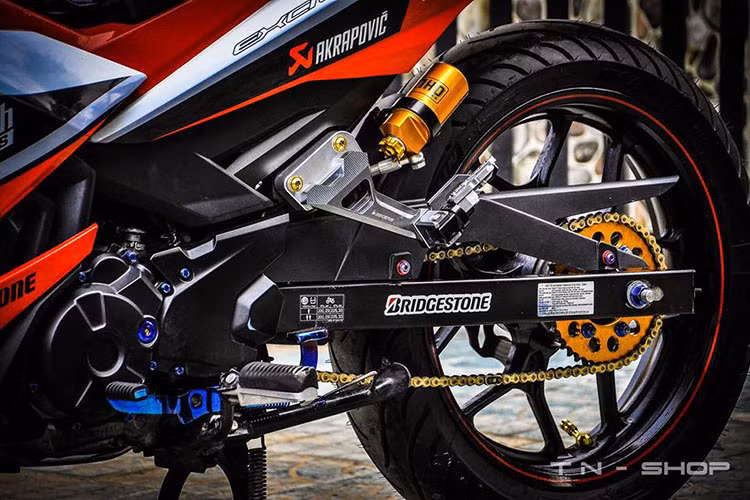  Dàn chân của Exciter 150 mạnh mẽ với gác chân Bikers CNC sắc sảo. Hàng loạt logo các thương hiệu phụ tùng xe cũng được đưa lên mang đầy màu sắc của xế đua phân khối nhỏ.