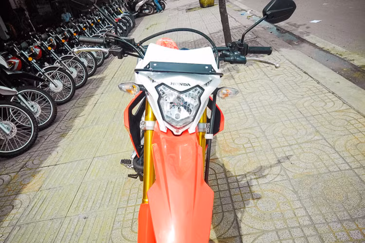 Cụ thể, ở phần đầu hãng xe máy Honda đã thiết kế cho CRF150 với đèn pha hình kiên kèm các đèn xi-nhan hai bên cùng ốp bảo vệ kiêm cả gió. Tuy nhiên các đèn này vẫn sử dụng bóng sợi đốt halogen thay vì đèn LED như nhiều mẫu xe mới đang bán ra thị trường hiện nay.