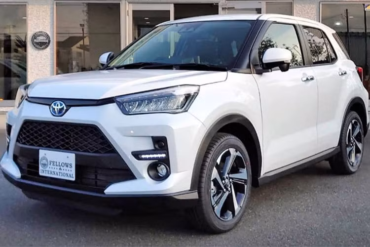 Xét về “ngoại hình” tổng thế, Toyota Raize Hybrid 2022 mới về cơ bản là tương tự bản thường với hướng thiết kế sắc cạnh, cứng cáp và rắn rỏi. Đầu xe vẫn sở hữu lưới tản nhiệt lục giác cỡ lớn mở rộng sang hai bên ở dưới, song hành cùng một đường cắt ở mép nắp capo nối liền với bộ đèn thiết kế vểnh lên trên.