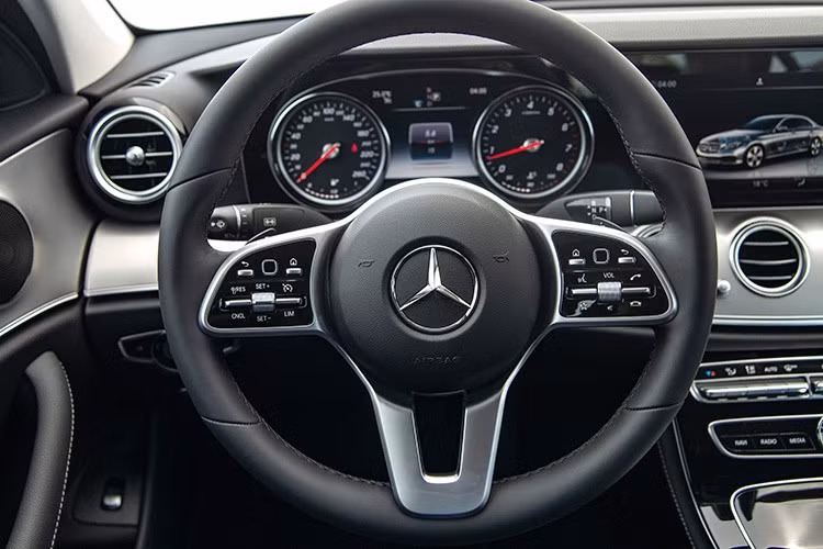 Vô-lăng trên Mercedes-Benz E180 được bọc da Nappa, mang đến cảm giác cầm rất mềm mại, được điều chỉnh điện 4 hướng tích hợp lẫy chuyển số phía sau. Giống như "đàn anh" là phiên bản E 200 2019, cụm đồng hồ trên phiên bản E180 cũng dừng lại ở dạng ống truyền thống với màn hình màu hiện thị thông tin ở chính giữa. Nếu khách hàng muốn bảng đồng hồ kỹ thuật số có thể tuỳ biến giao diện, E200 Exclusive sẽ là sự lựa chọn.