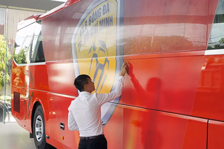 Quyền Chủ tịch CLB bóng đá TP HCM - Lê Công Vinh cẩn thận kiểm tra lại logo của đôi bóng được in khá lớn trang trí bên ngoài xe buýt. 