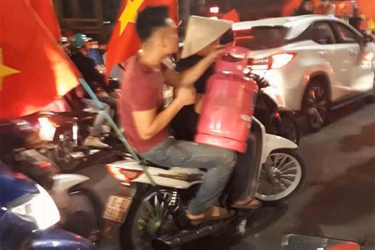 Những thanh niên quá khích còn cưỡi cả xe máy, mang theo bất kỳ vật dụng gì có thể phát ra âm thanh, thậm chí là lửa... Trong ảnh là một thanh niên đi xe máy đầu trần ôm bình ga xuống đường được xem là hình ảnh không đẹp, thậm chi xấu xí và gây nguy hiểm đến tính mạng.