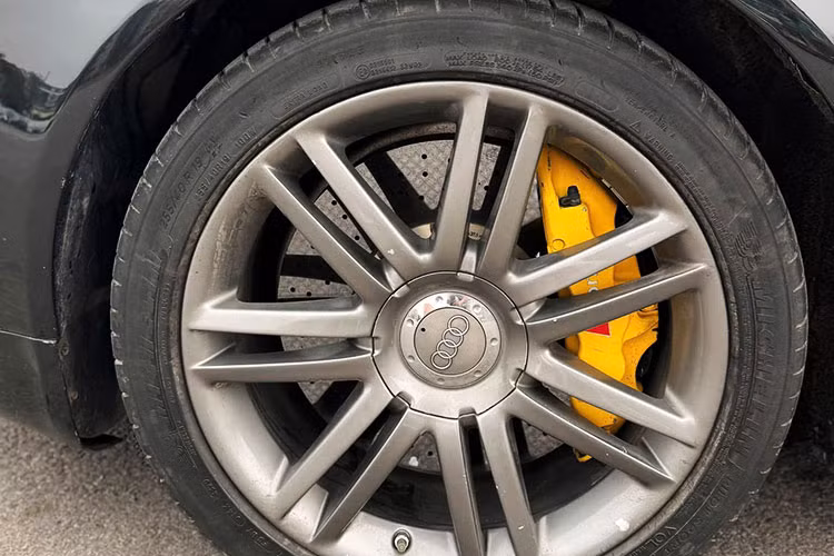 Chiếc Audi S8 2008 đời cũ rao bán này được sơn màu đen bóng, mang lại vẻ ngoài sang trọng. Lớp sơn vẫn bảo toàn độ sáng bóng, chỉ có chóa đèn pha hơi ngã vàng nhẹ do tuổi đời cao. Xe được trang bị bộ mâm đa chấu kết hợp với cùm phanh vàng, tạo điểm nhấn thể thao.