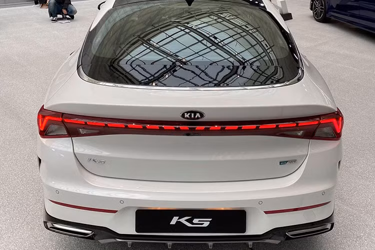 Đầu xe K5 All New vẫn trung thành với lưới tản nhiệt hình mũi hổ, song đã có tạo hình tràn viền đầy mới mẻ với dạng vân sóng bắt mắt. Nối liền lưới tản nhiệt là cặp đèn pha LED với 3 bóng xếp xếp tầng mới. Ấn tượng nhất phải kể đến phần đuôi xe với dải đèn LED đứt chạy ngang khoang hành lý mô phỏng thiết kế của những chiếc xe hạng sang nối liền đèn hậu mang đến vẻ thống nhất cho khu vực này.