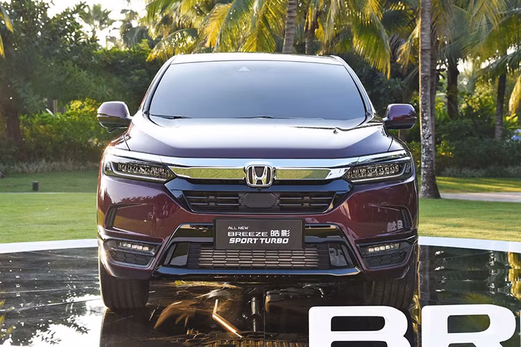 Được áp dụng ngôn ngữ thiết kế Solid Wing Face, Honda Breeze 2020 có thanh mạ crôm dày dặn trên lưới tản nhiệt nối liền với cụm đèn pha thanh mảnh. Bên trong cụm đèn pha này là các bóng đèn có thiết kế như đá quý khá ấn tượng. Bên dưới là hốc gió màu đen và đèn sương mù hình tròn. Chưa hết, hãng Honda còn trang bị ốp màu đen kéo dài từ hốc đèn sương mù đến cản sau. Điều ngạc nhiên là Honda Breeze không hề có nẹp màu đen bao quanh hốc bánh như người anh em CR-V.
