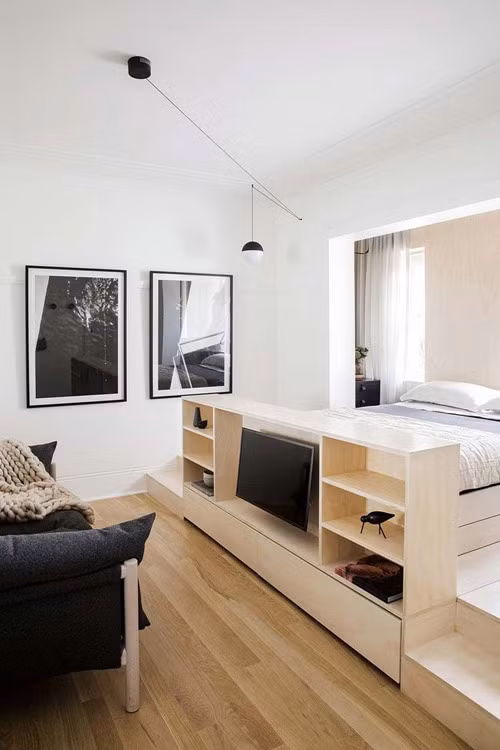 Vì diện tích nhỏ nên căn hộ nhỏ 22m2 cũng không dùng tường ngăn và tận dụng ngay các đồ nội thất để ngăn cách các khu vực chức năng. Chẳng hạn như chiếc kệ tủ này vừa là nơi đặt tivi, vừa là vùng ngăn cách giữa khu vực tiếp khách với phòng ngủ.
