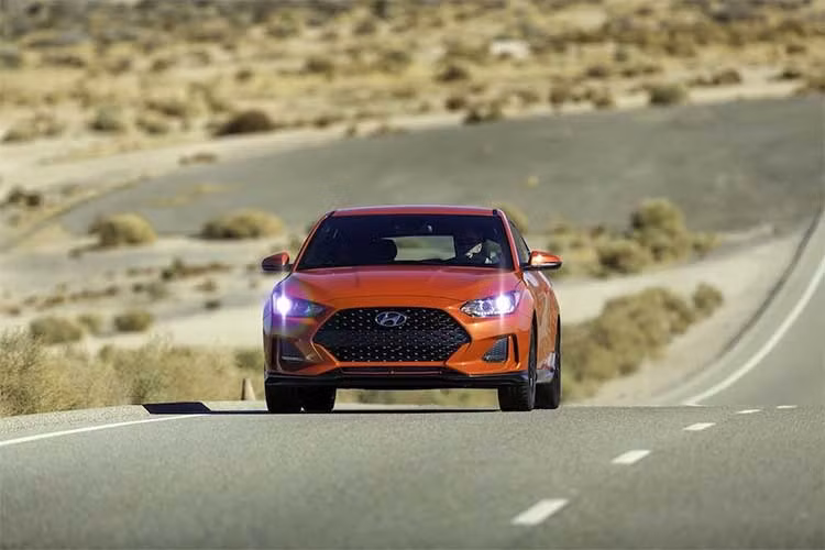 Sự mạnh mẽ là chủ đề chính mà Hyundai hướng tới với phần đầu của Veloster 2019. Ngoài lưới tản nhiệt vân tổ ong có hình lục giác lớn, chiếc xe còn có các khe gió ở hai bên và cánh khuếch tán khí động học lắp sẵn dưới cản trước. Cụm đèn pha có bóng chính dạng thấu kính projector cùng dải LED ban ngày ở phía dưới...