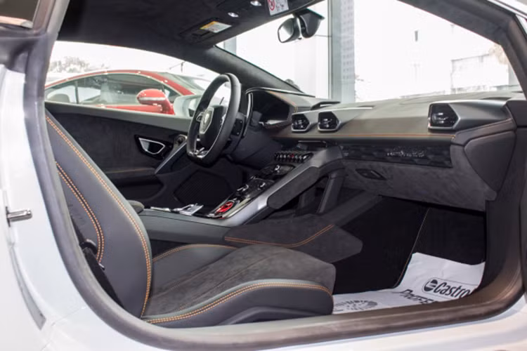 Đối lập với bộ áo trắng Bianco Monocerus, chiếc siêu xe Lamborghini Huracan LP610-4 đang rao bán có nội thất bọc da Alcantara đi kèm các chi tiết may chỉ cam ở ghế ngồi. Xe được trang bị màn hình cảm ứng 8.4 inch được đặt ở trung tâm bảng điều khiển. Màn hình này có thể cảm ứng đa điểm, Apple CarPlay tích hợp, kết nối định vị và hơn thế nữa.