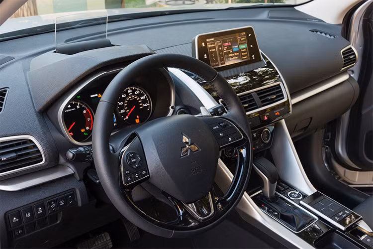 Bên trong nội thất, bảng táp-lô của Eclipse Cross thiết kế chia tầng rõ rệt. Những đường viền ốp chạy ngang bảng táp-lô, cắt dọc từ bệ trung tâm màu kim loại đem tới cho xe cảm giác hiện đại, năng động hơn. Vô-lăng trên mẫu xe này thiết kế 3 chấu, bọc da được lấy cảm hứng từ Outlander.