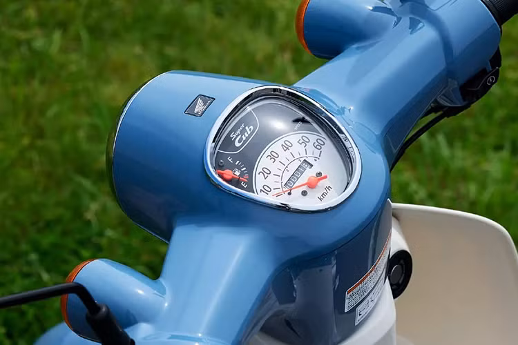 Viền đồng hồ và nắp ống xả được mạ crôm, phối hợp cùng hai tông màu xám đen tạo cảm giác sang trọng và hoài niệm. Đây là sự kết hợp hoàn hảo giữa cổ điển và hiện đại, khẳng định nét đặc trưng khó lẫn của dòng xe Super Cub.