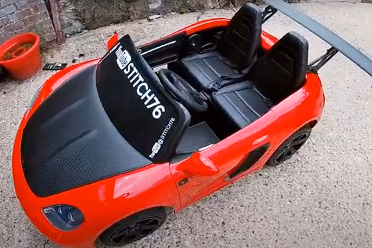 Chiếc xe đồ chơi chạy phố ở đây không phải là xe đồ chơi Power Wheels, nhưng nó là một sản phẩm tương tự: một chiếc xe đồ chơi Super Sport XXL, còn được tiếp thị là xe Super Car XL hoặc YSA-021.