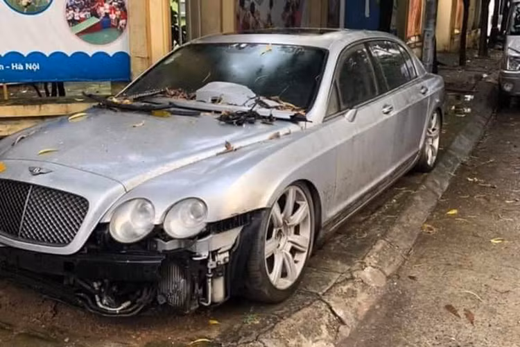 Một chiếc xe siêu sang Bentley Continental Flying Spur trong tình trạng vỡ nát phần vỏ phía đầu đang nằm trên vỉa hè một con phố tại khu vực Mỹ Đình, Hà Nội. Đối với giới thạo tin, không khó để nhận ra chiếc Bentley này từng xuất hiện trong một bãi gửi xe trong nhiều năm liền trước khi được đưa ra ngoài.