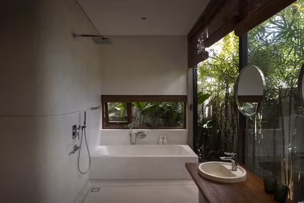Phòng tắm mang phong cách thư giãn, hòa cùng thiên nhiên nhờ các cửa kính lớn và cây xanh xung quanh. Ảnh: SuKha_Studio