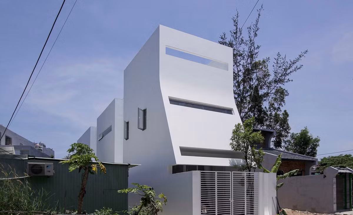Mặt tiền căn nhà thiết kế tối giản cong chạy dọc từ tầng cao nhất xuống cổng, tạo cảm giác như dòng chảy của nước. Mặt cong vừa hạn chế diện tích vùng tiếp xúc với nắng, vừa đảm bảo tính thẩm mỹ. Ảnh: Nguyễn Đình