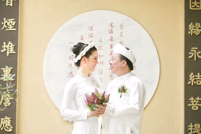 Hai vợ chồng cô đều chọn lựa trang phục truyền thống màu trắng. Chú rể cài hoa sen trên ngực và cả hai cùng đón nhận sự chúc phúc của bạn bè, người thân.