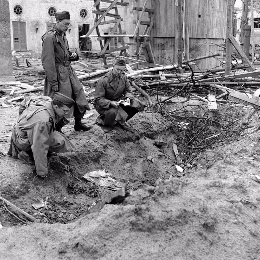 Các phóng viên kiểm tra nơi thi thể vợ chồng Hitler được hỏa thiêu bằng xăng trong khu vườn của dinh Thủ tướng. Trước đó, binh sĩ Liên Xô đã tìm thấy một vài mảnh xương còn sót lại của Hitler tại nơi này.