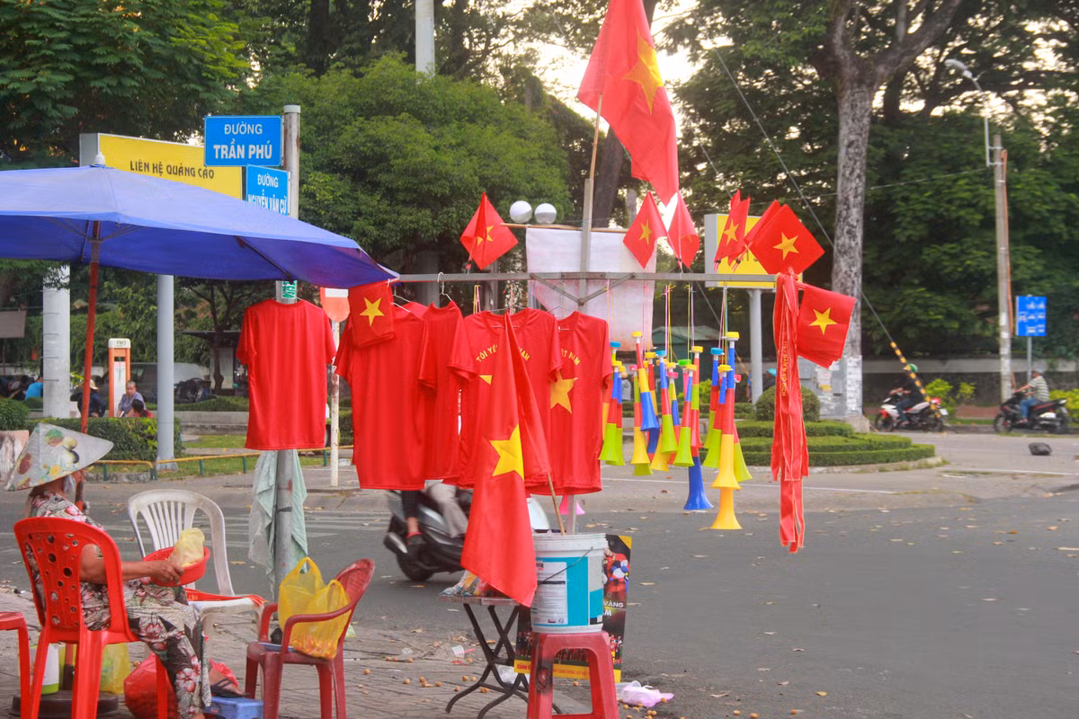 Để chuẩn bị cho trận đấu vào lúc 19h hôm nay, ngay từ sáng sớm, nhiều người kinh doanh các phụ kiện cổ vũ đội tuyển Việt Nam đã chọn vị trí, bày biện các mặt hàng như kèn, cờ đỏ sao vàng, áo in cờ Việt Nam cùng nhiều phụ kiện khác để bán phục vụ cho các cổ động viên. Theo một người kinh doanh trên đường Hùng Vương, mỗi một lá cờ to có giá khoảng 100 nghìn đồng, áo cờ đỏ sao vàng có giá từ 80-120 nghìn đồng.
