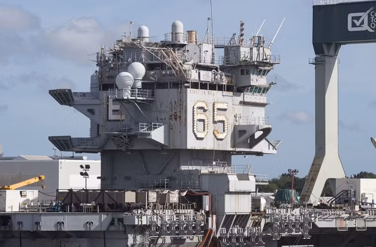 "Với lượng giãn nước gần 94.781 tấn, USS Enterprise đòi hỏi khối lượng công việc lớn chưa từng có để hoàn tất quá trình tháo dỡ. Dù hải quân Mỹ chọn phương án nào đi nữa, CVN-65 cũng sẽ trở thành tiền đề cho các quy trình và mức giá xử lý những siêu tàu sân bay lớp Nimitz, dự kiến bị loại biên từ giữa thập niên 2020", đại diện GAO cho biết. Nguồn ảnh: Virginian-Pilot.
