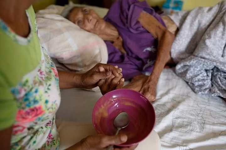 Judith Palmar đã phải đưa mẹ già Sibilina Caro bị liệt ra bên ngoài nhà do bên trong quá nóng sau khi mất điện và không thể chạy được máy điều hòa nhiệt độ.